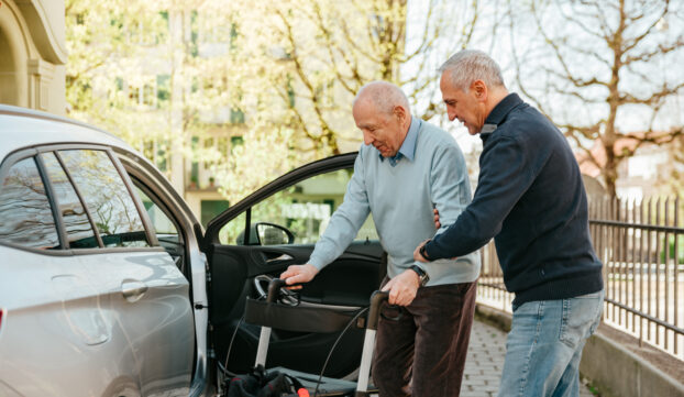 Un bénévole Transport Croix-Rouge aide son bénéficiaire à entrer dans la voiture.